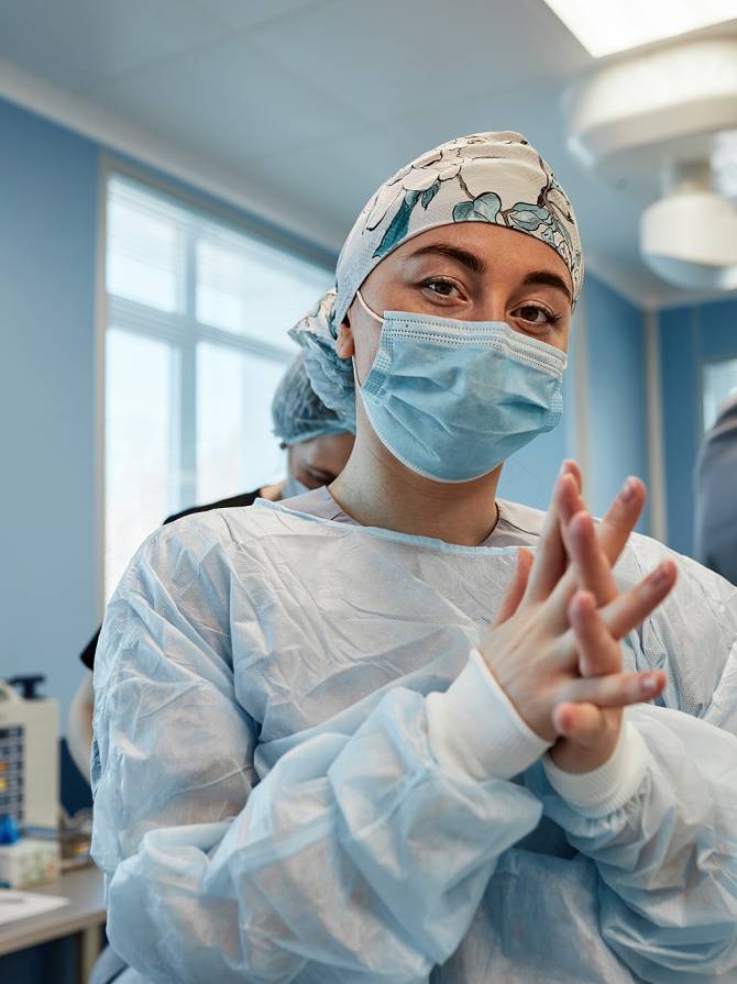 A team of surgeons is preparing for surgery. Surgeons wear sterile clothing before surgery with the help of nurses, sterile gowns, gloves, masks, in the intensive care unit